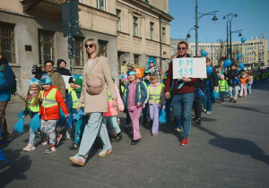 Dzieci maszerują w niebieskich opaskach na głowach.