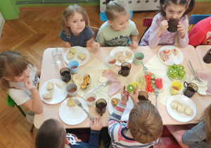 Dzieci samodzielne szykują śniadanie z produktów ustawionych na stole