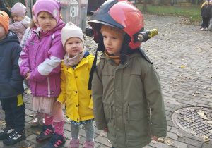 Chłopiec pozuje w kasku strażackim.