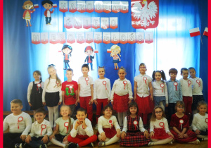 Dzieci pozują do grupowego zdjecia na tle dekoracji.