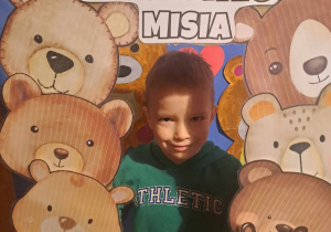 Chłopiec uśmiecha się do zdjęcia w fotoramce z misiami i napisem