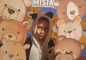 Chłopiec uśmiecha się do zdjęcia w fotoramce z misiami i napisem