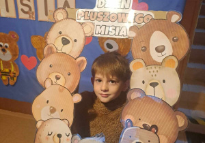 Chłopiec uśmiecha się do zdjęcia w fotoramce z misiami i napisem