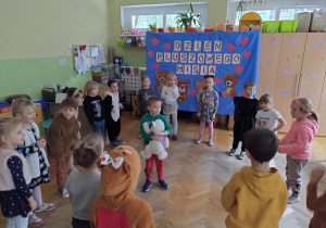 Dzieci stoją w kole i biorą udział w zabawie podczas balu