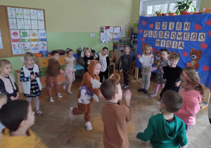 Dzieci stoją w kole i biorą udział w zabawie podczas balu