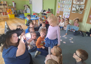 Nauczycielka podświetla latarką kartę i odczytuje znaczenie symbolu