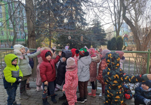Grupa dzieci przygląda się przygotowanej przez siebie ptasiej stołówce
