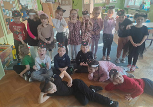Grupa dzieci przebrana za kolty lub w opaskach kota pozuje do zdjecia