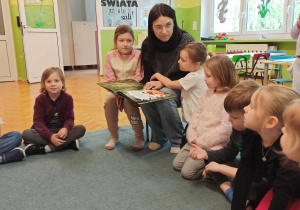 Dzieci siedzą na dywanie.