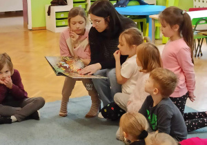 Dzieci siedzą na dywanie.