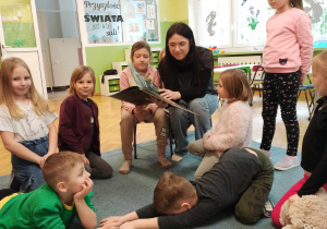Dzieci siedzą na dywanie.