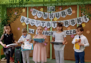Czwórka dzieci pozuje na tle dekoracji.