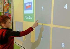 Chłopiec otwiera kartę w grze memory. Jedna z kart to symbol narodowy-flaga Polski.