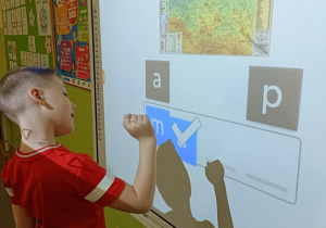 Chłopiec w czerwonej koszulce układa wyraz "mapa".