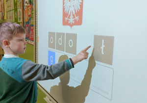 Chłopiec w turkusowej bluzie układa wyraz "godło".