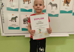 Chłopiec pozuje do zdjęcia z dyplomem