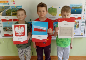 Trzech chłopców pozuje z symbolami narodowymi.