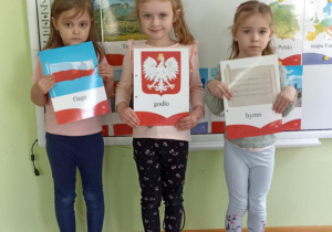 Trzy dziewczynki pozują do zdjęcia z symbolami narodowymi.