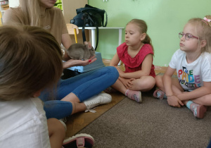 Pani prowadząca trzyma w dłoni szynszyle. Dwie dziewczynki siedzą obok niej.