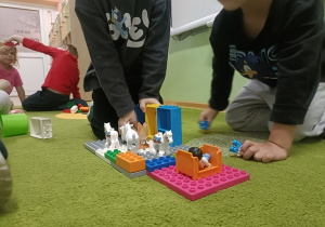 Na zielonym dywanie stoi budowla z klocków lego DUPLO