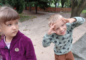 Chłopiec w bluzie z myszką miki uśmiecha się do zdjęcia. Obok stoi dziewczynka w fioletowej bluzie.