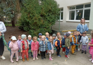 Dzieci stoją na betonie. W tle widać budynek przedszkola.