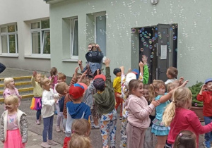Dzieci łapią bańki mydlane.
