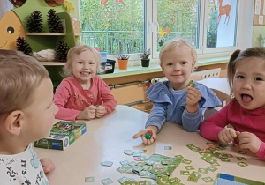 Czwórka dzieci siedzi przy stoliku i gra w grę "Superfarmer"