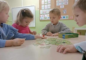Czwórka dzieci siedzi przy stoliku i gra w grę "Superfarmer"