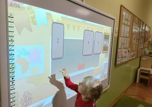 Dziewczynka w czerwonej sukience dotyka ekranu.