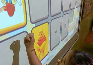 Dziewczynka w ciemnych włosach dotyka ekranu.