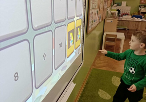 Chłopiec w zielonej bluzce dotyka ekranu.