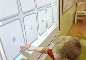 Chłopiec dotyka karty z cyfrą "8"