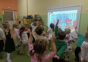 Dzieci naśladują ruchy pokazywane na ekranie.