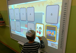 Chłopiec w bluzce w paski dotyka ekranu.