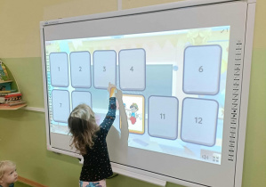 Dziewczynka w bluzce w kropki dotyka ekranu.