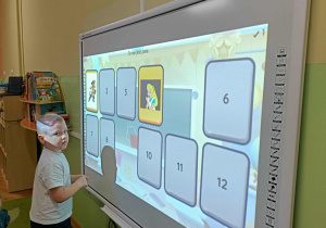 Chłopiec w białej bluzce dotyka ekranu.