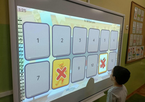 Chłopiec w białej bluzce z długim rękawem dotyka ekranu.