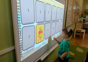 Chłopiec w turkusowej bluzce dotyka ekranu.