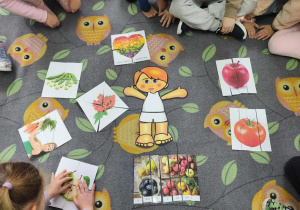 Dzieci układają puzzle na dywanie. Po środku leży szablon człowieka.