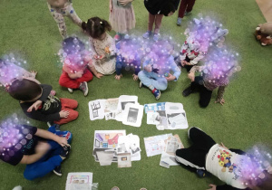 Dzieci siedzą na dywanie i dopasowywują karty do siebie.