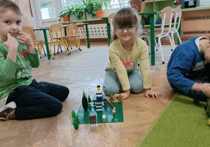 Dziewczynka w okularach i chłopiec pozują ze skończoną budowlą.