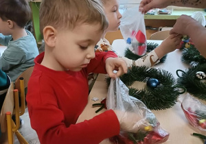 Dwóch chłopców siedzi przy stole i wykonuje wianki.