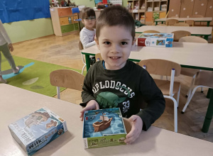 Chłopiec siedzi przy stoliku i gra w grę planszową.