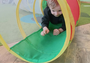 Chłopiec w czarnej bluzie przechodzi przez kolorowy tunel.