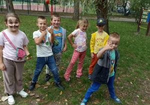 Szóstka dzieci stoi na trawie. Na twarzach mają makijaże.