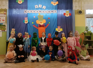 Grupa dzieci stoi na tle dekoracji.