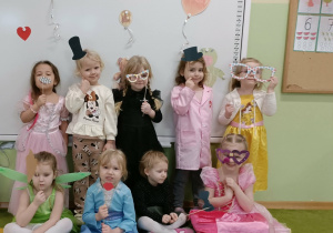 Grupa dziewczynek na tle dekoracji. W rączkach trzymają gadżety do fotobuduki.