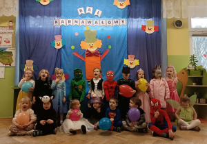 Grupa dzieci stoi na tle dekoracji.