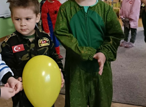 Dwóch chłopców pozuje do zdjęcia. Jeden z chłopców trzyma w dłoni żółty balonik.